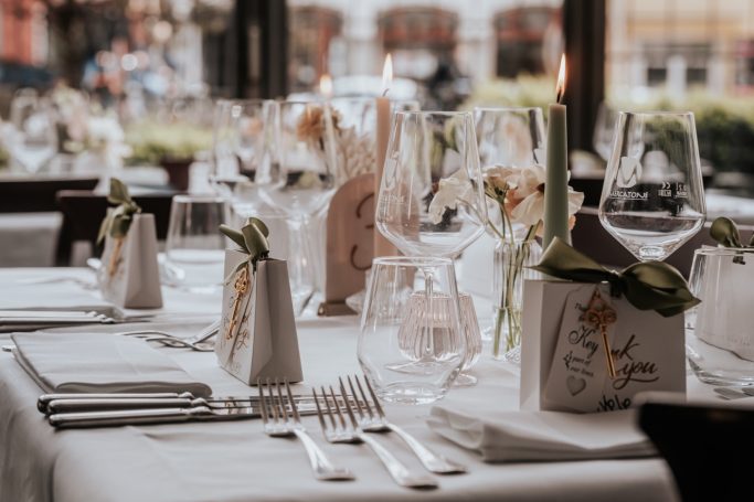 Elegante gedeckte Tische mit Geschirr, Gläsern und Blumendekorationen in einem Restaurant.